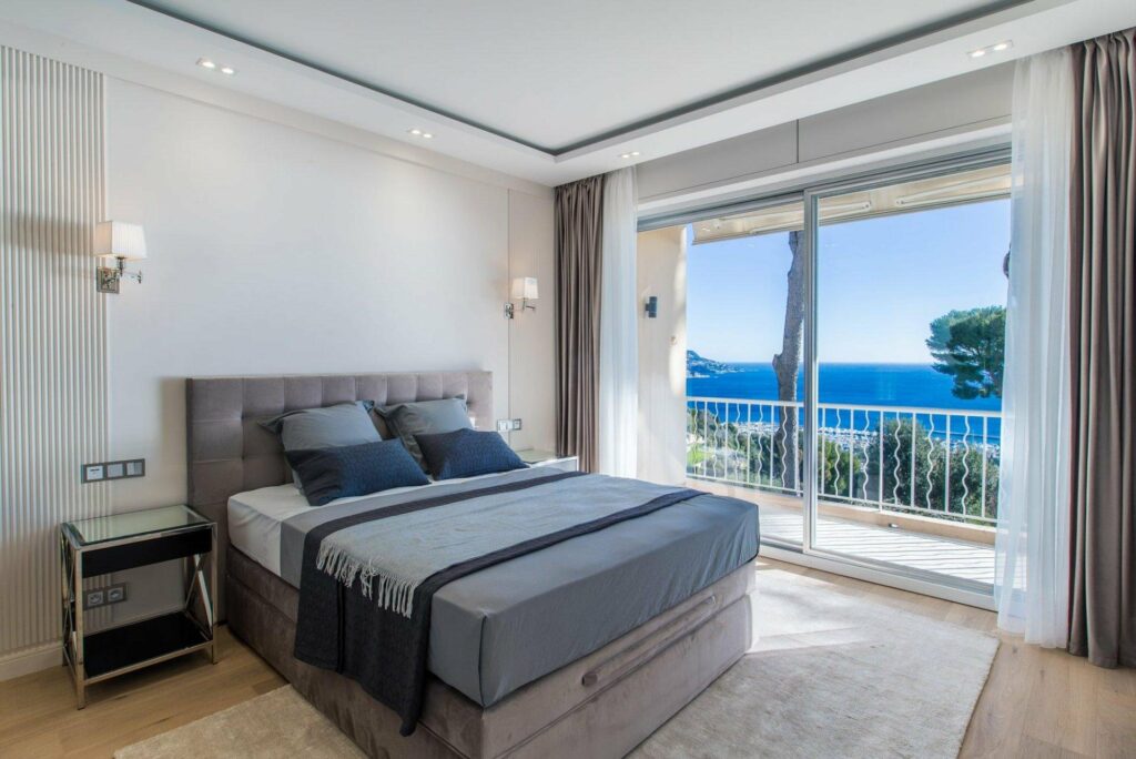 bedroom with queen size blue bed with access to terrace with sea view