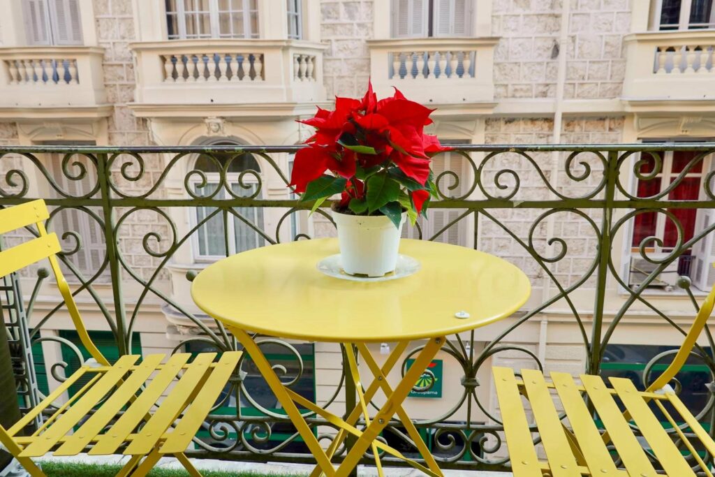 balcony with city view in nice with yellow table and red flowers in center