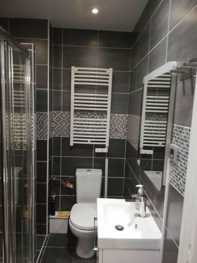 bathroom with black and white tile walls and floors with standing glass shower