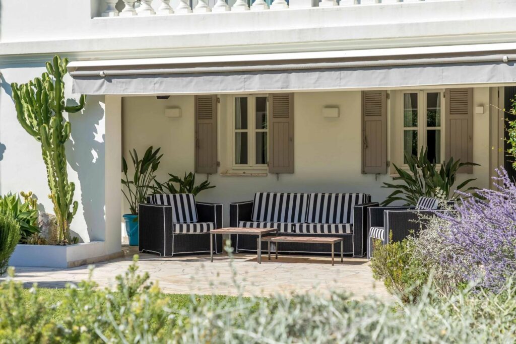 backyard porch with navy blue and white sofa facing vibrant garden