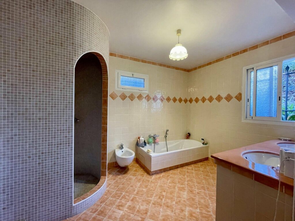 bathroom with peach tile floors and white bathtub in corner