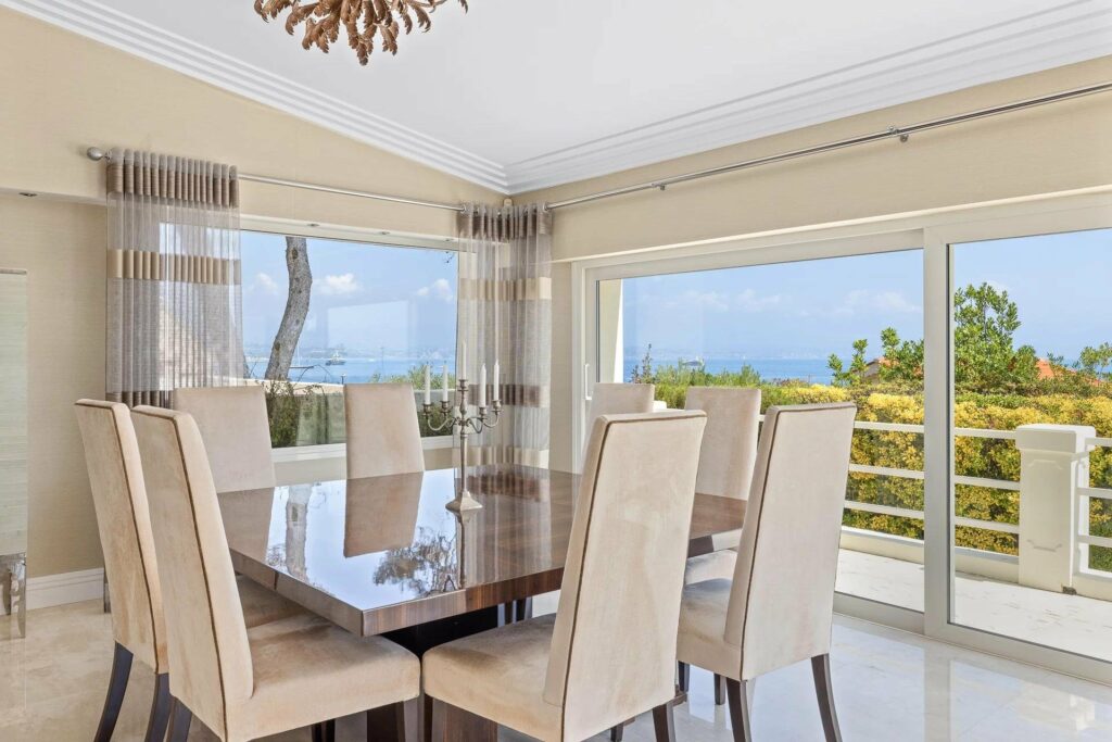 dining room with glass table with beige chairs and large windows with sea view