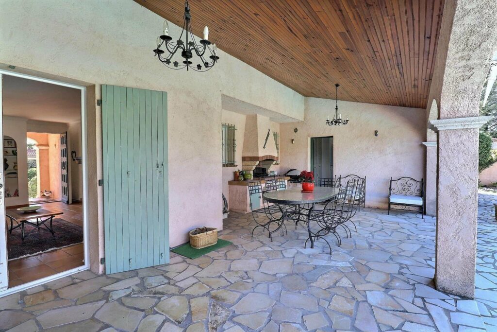 backyard with stone floor porch and teal door and black hanging chandelier