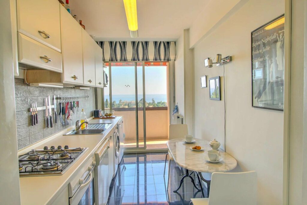 kitchen with white cabinets and shiny white tile floors and sliding door to balcony