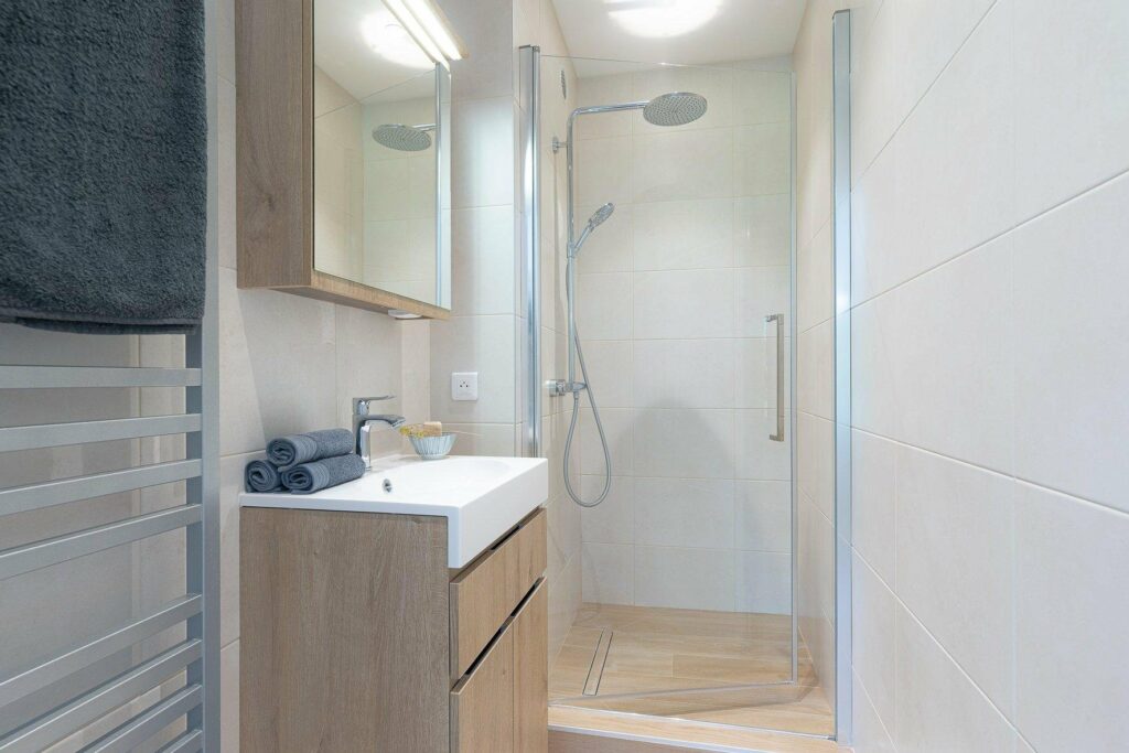 bathroom with standing shower and light wooden drawers