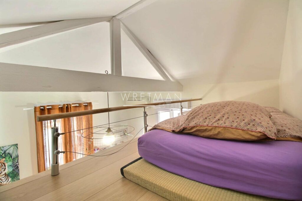 mezzanine style bedroom with queen size bed with purple bedding and light wood floors