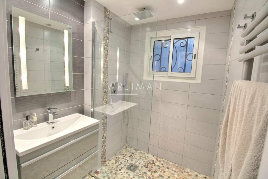 bathroom with light grey tiling and small stone tile floors