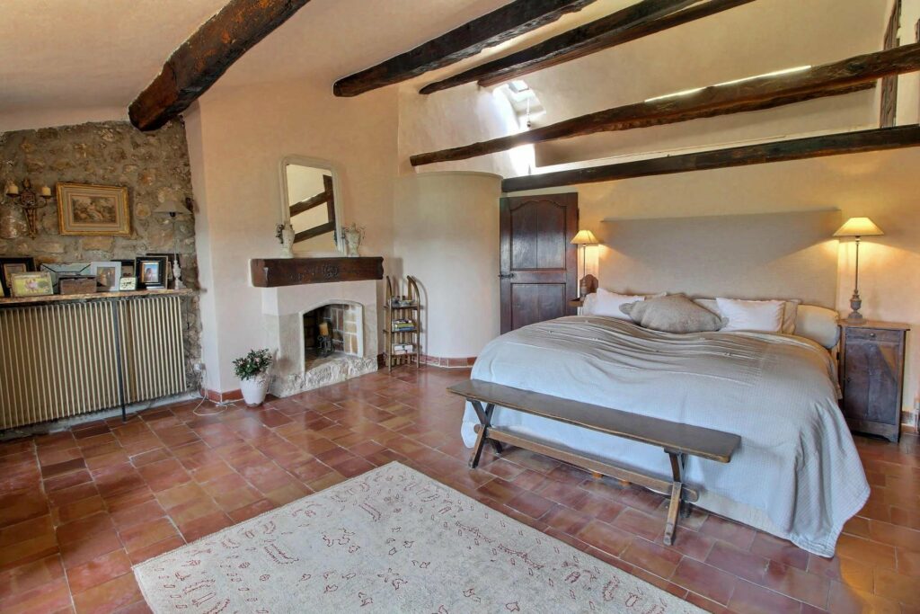 bedroom of village house with exposed wooden beams and terracotta tile floors