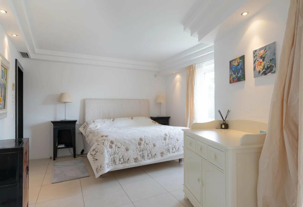 bedroom with queen size bed with white floral bedding next to window with garden view