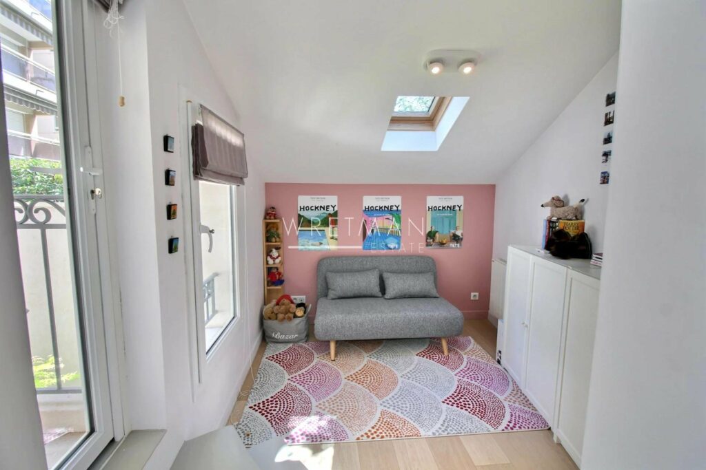 living room with pink and purple printed rug and small grey couch