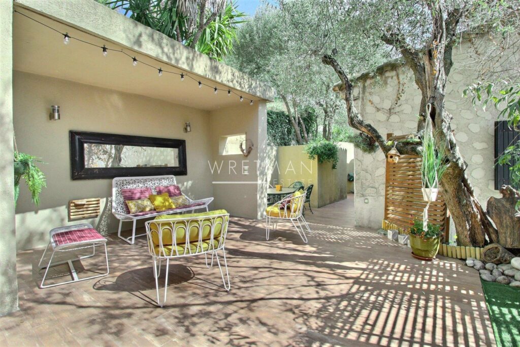 backyard with stone floors and and yellow and pink furniture next to tree