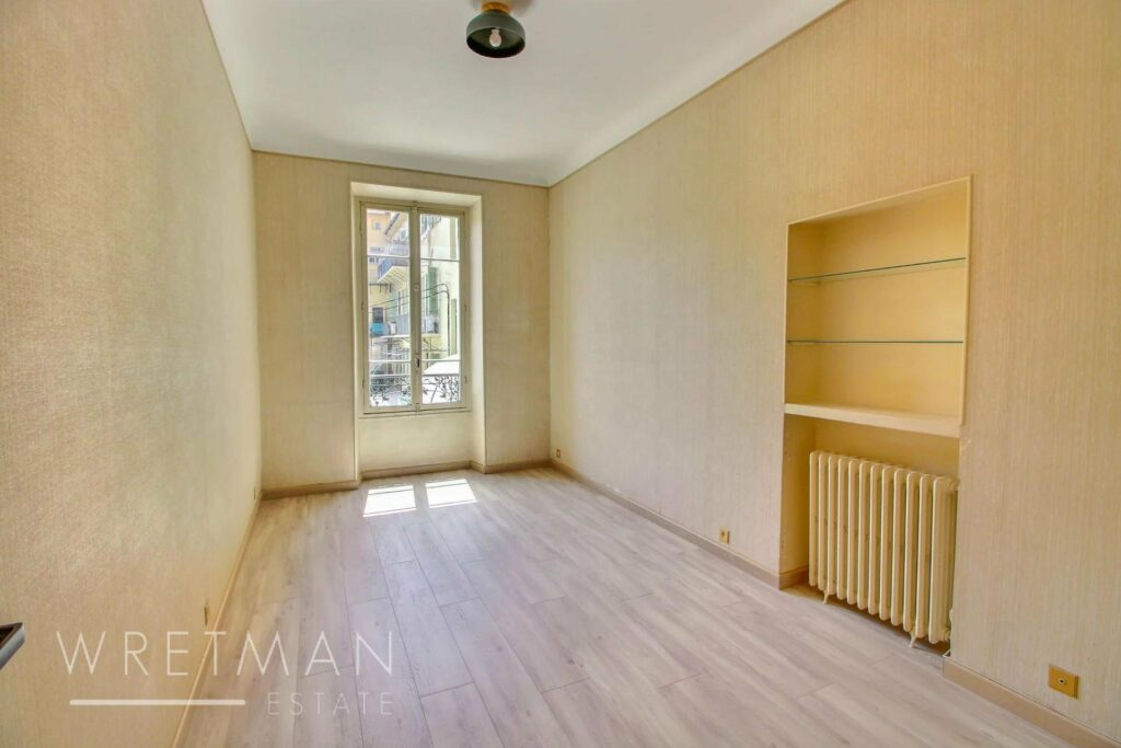 living room with pale yellow walls and wooden floors and shelves in corner