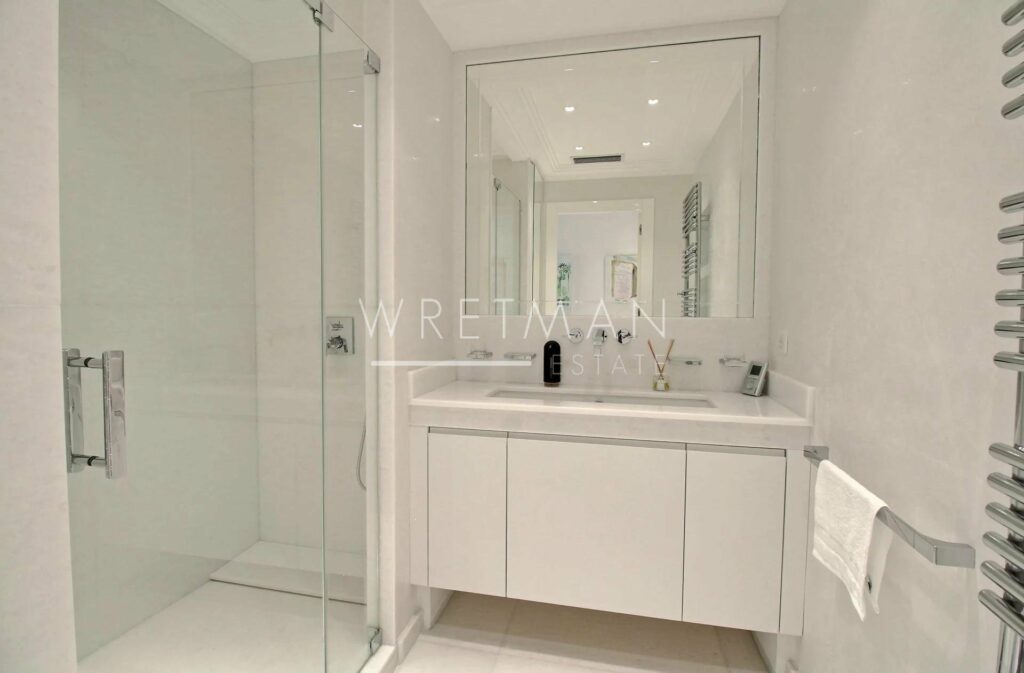 bathroom with all white design with white cabinets and large standing glass shower