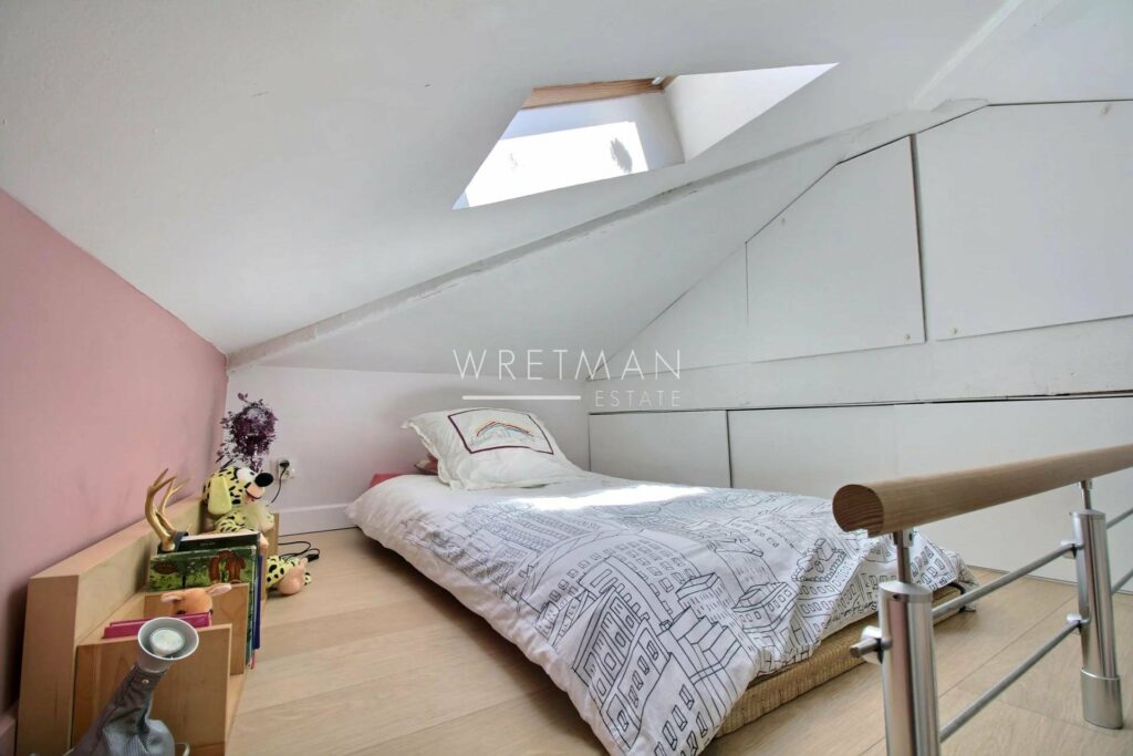 loft style bedroom with single bed and light purple printed bedding and light wood floors