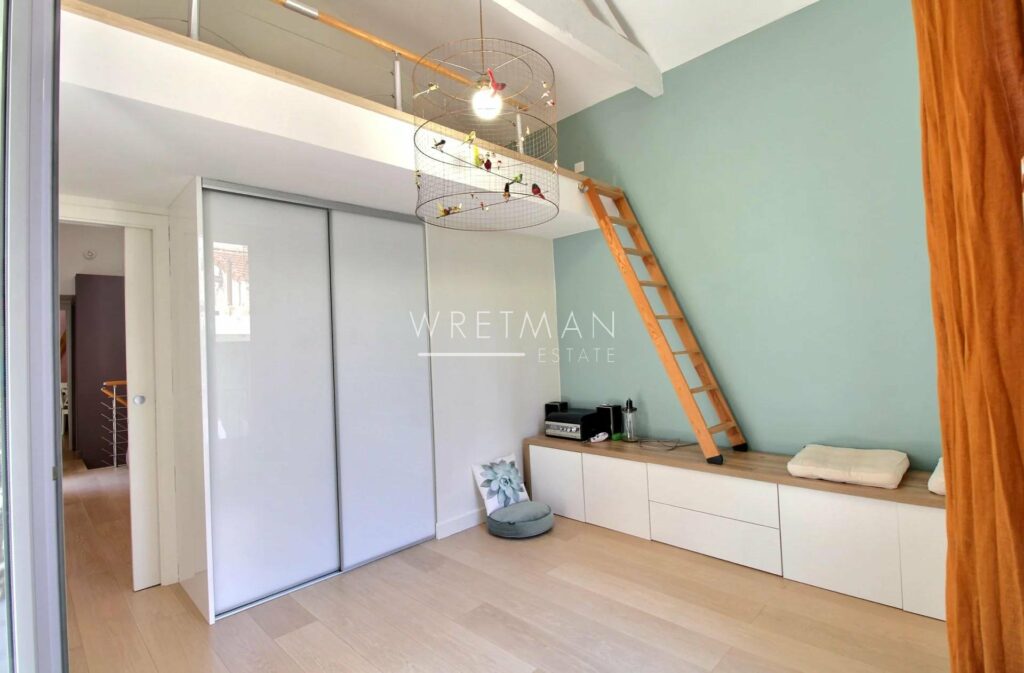 room with light blue walls and white closet space with wooden ladder leading up to mezzanine
