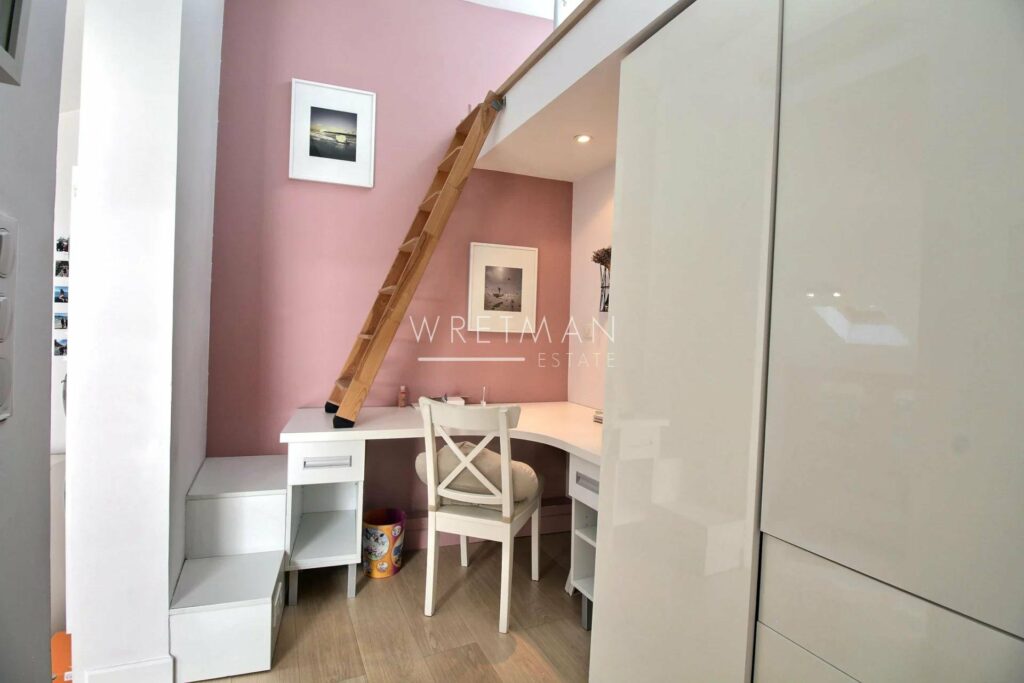 home office of apartment for sale in cannes with white desk and chair and light pink walls