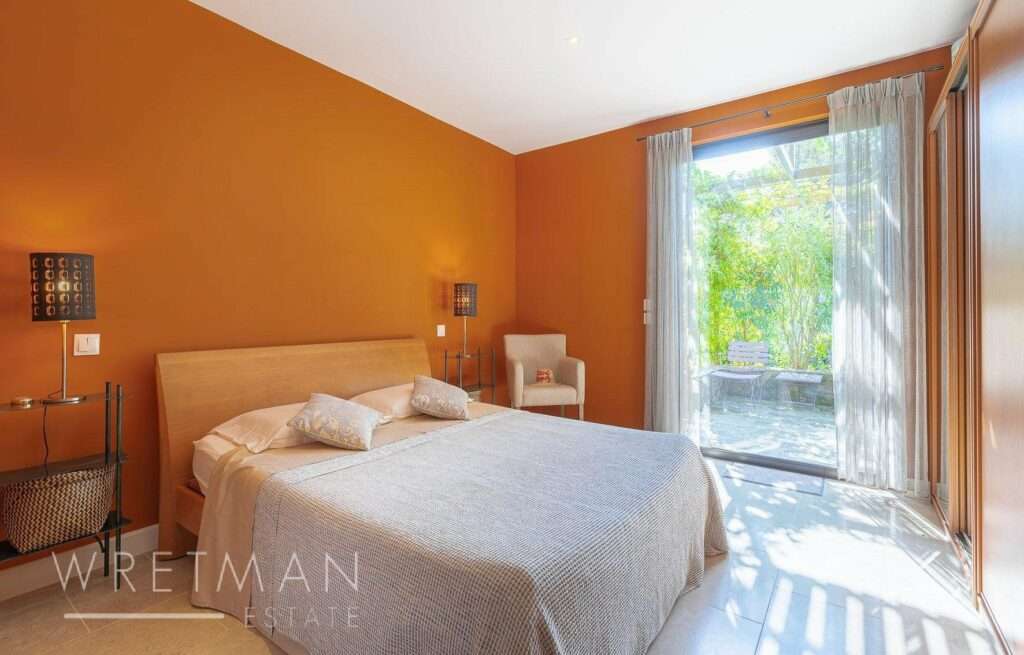 bedroom with queen size bed and orange walls with terrace through sliding glass doors
