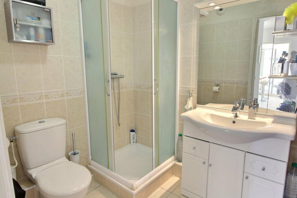 bathroom with light blue tiling with small standing shower