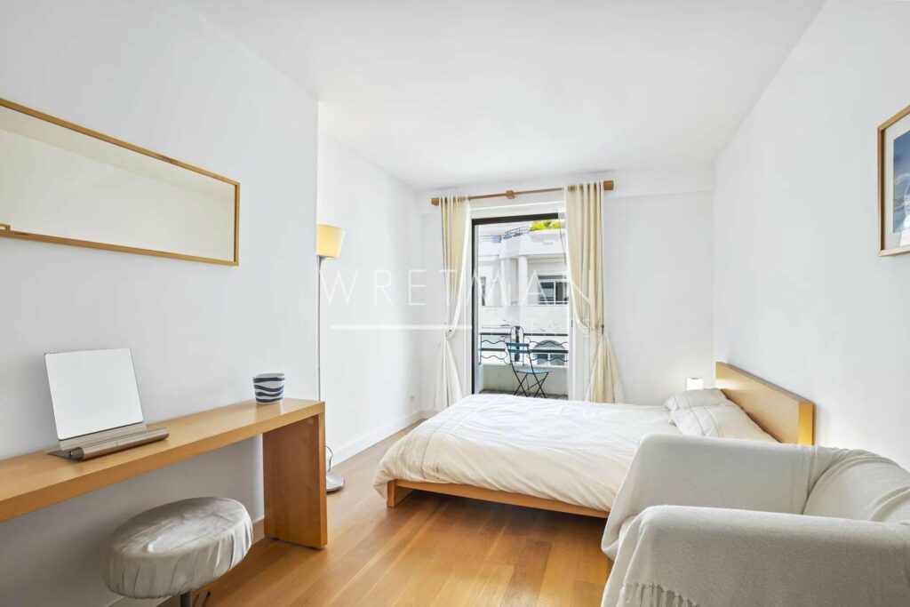 bedroom with wood floors and queen size bed with small balcony facing the city center