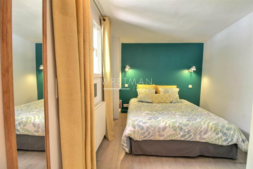 bedroom with blue floral bedding and blue wall with two small overhead lights