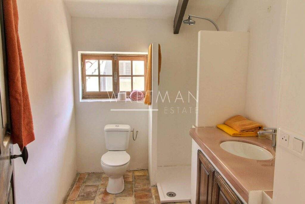 small bathroom with stone floors and small window with wooden frame