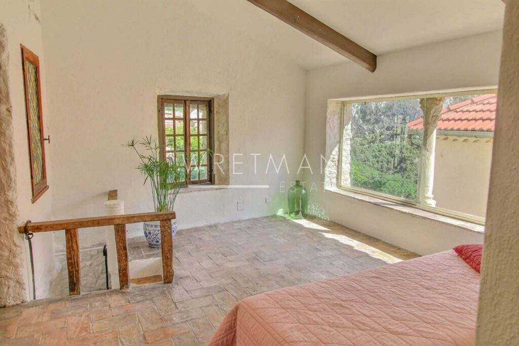 bedroom with stone tile floors and two windows with view of garden