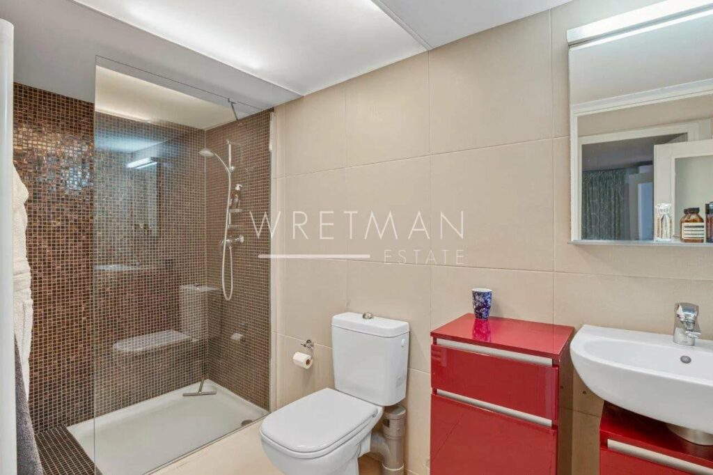 bathroom with large standing shower with small brown tiling and red cabinet