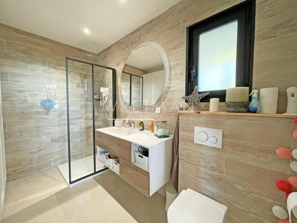 bathroom with light brown tiling and large open shower with glass door