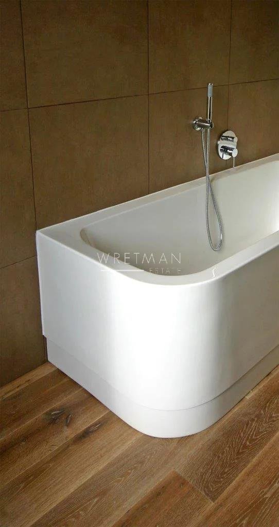 bathroom with large white bath tub with wood floors