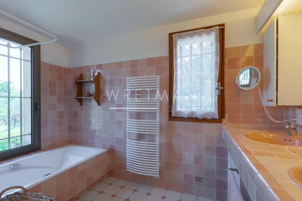 bathroom with pink tiling and bath tub in corner