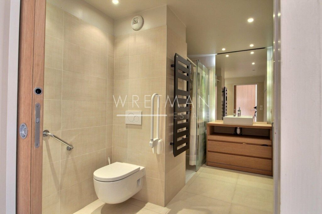 open bathroom with beige tiling with wooden drawers underneath single sink with large mirror