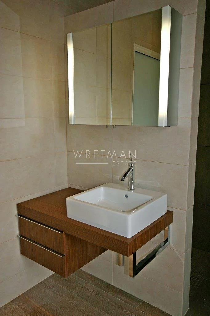 bathroom with wooden sink and single sink bellow square lit mirror