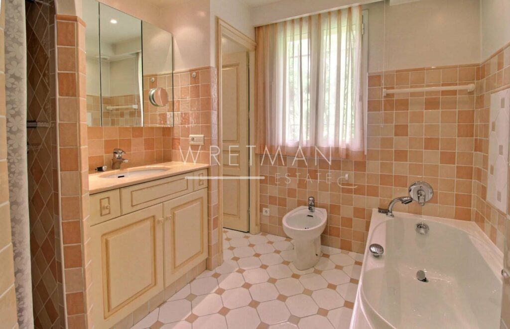 bathroom with white and pink tiling and white bath tub