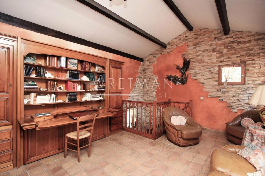 office with wooden desk and shelves filled with book and high ceilings with exposed wood beams