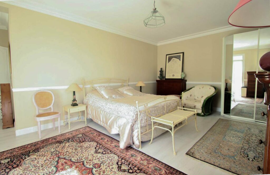 bedroom with queen size bed and white satin sheets and red oriental rug