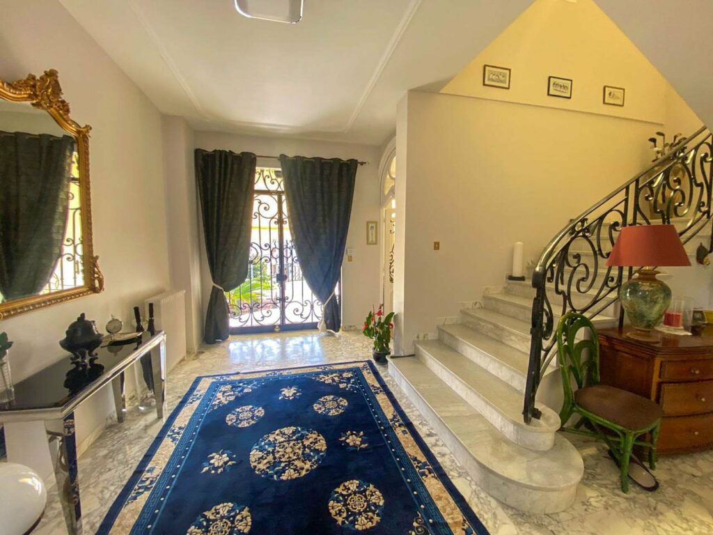 entrance of villa with marble floors and large staircase with blue rug