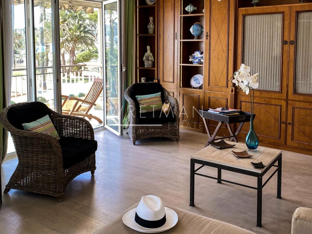 living room with 2 brown wicker chairs in corner and open glass door to terrace