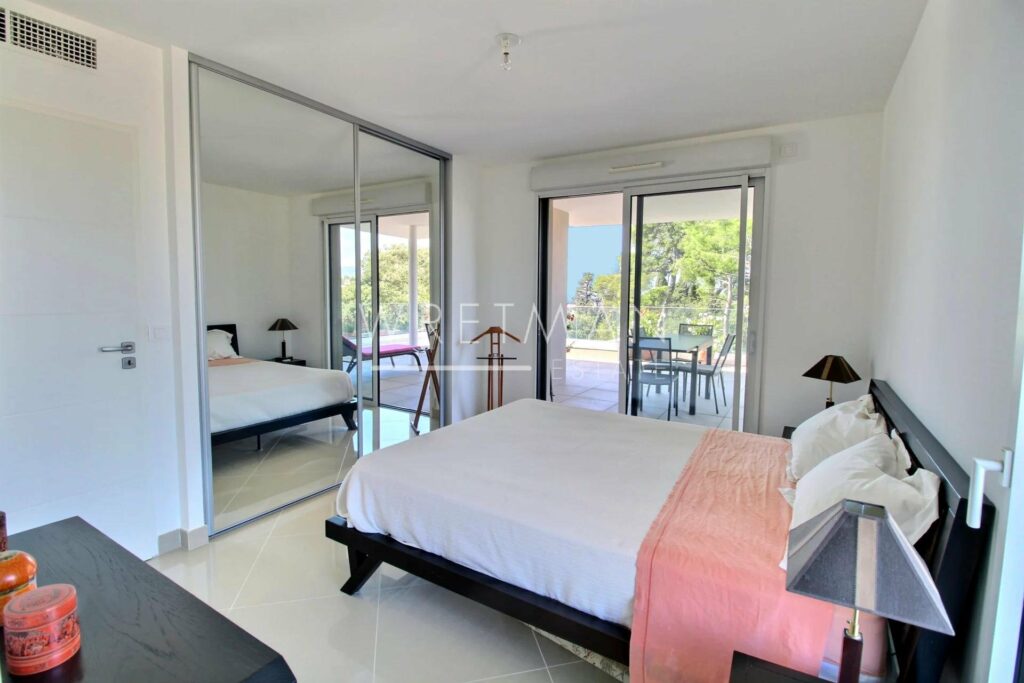 bedroom with king size bed with white and pink bedding next to sliding glass doors to terrace