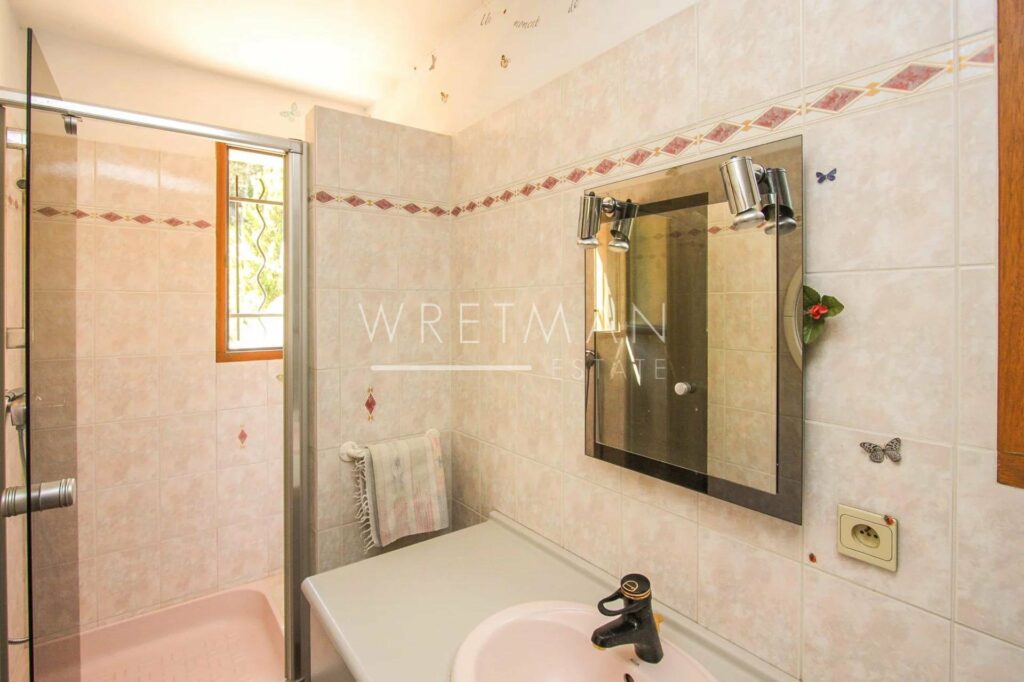 bathroom with beige and pink tiling and shower in corner