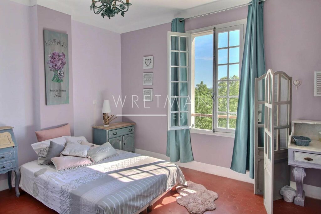 bedroom with queen size bed with white bedding and large window with view of garden