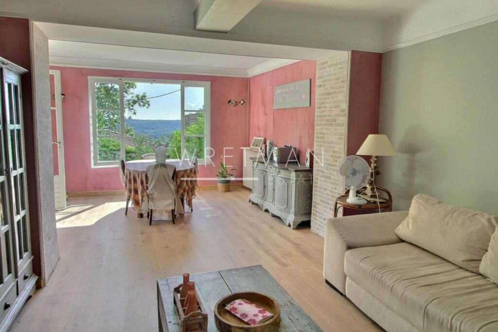 living room with wood floors and pink walls and grey couch and large window with mountain view