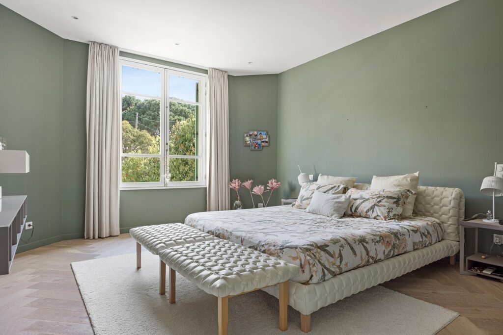 bedroom with sage green walls and white leather bed frame