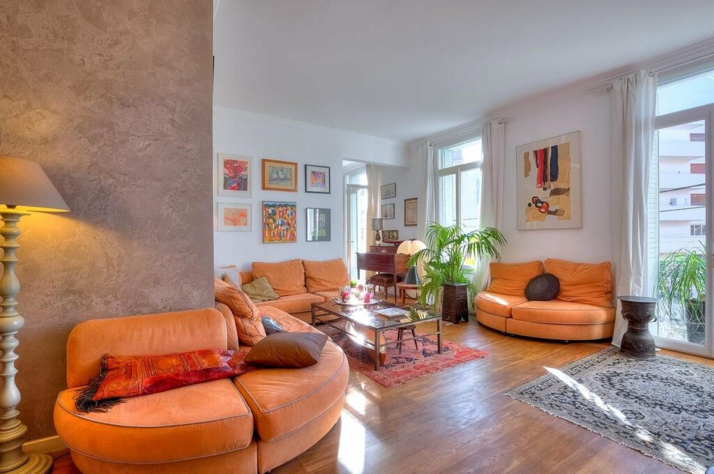 living room with orange couch and glass center table and plant in corner