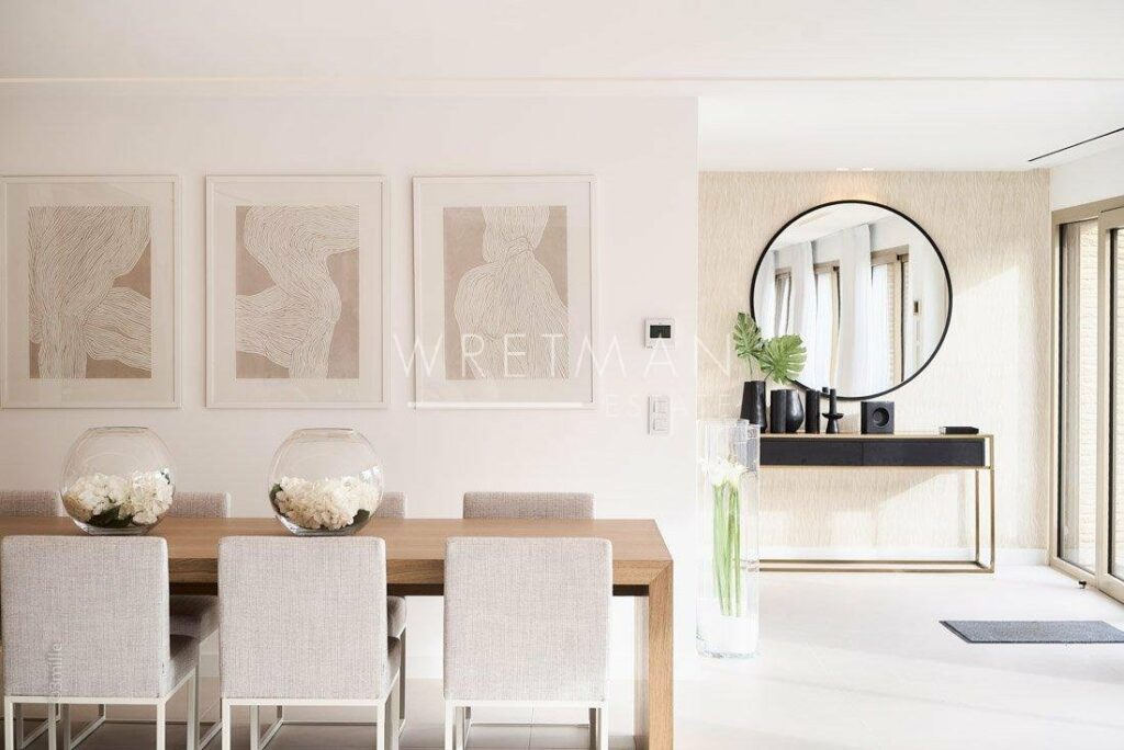 dining room with neutral tones and two large paintings hanging on wall