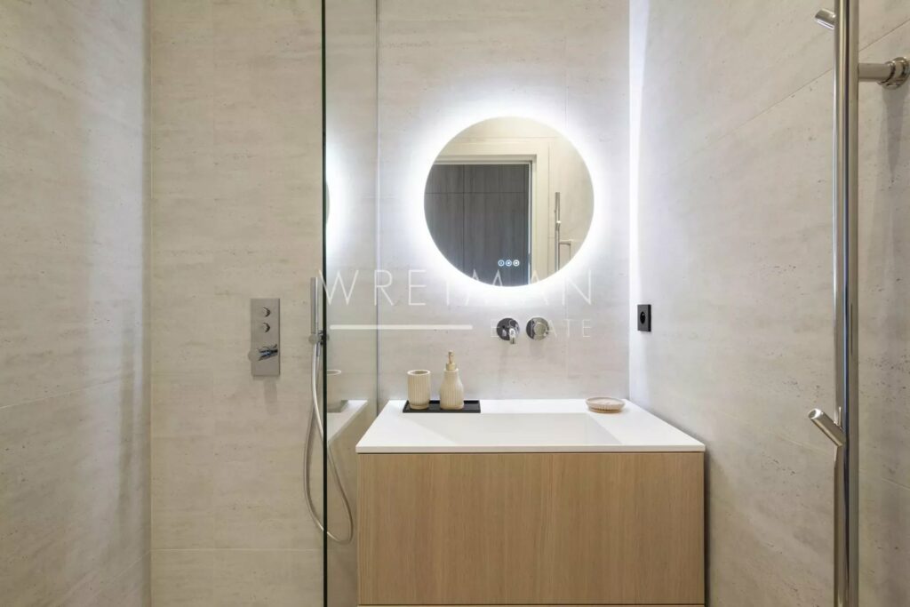 bathroom with round lighted mirror and single sink
