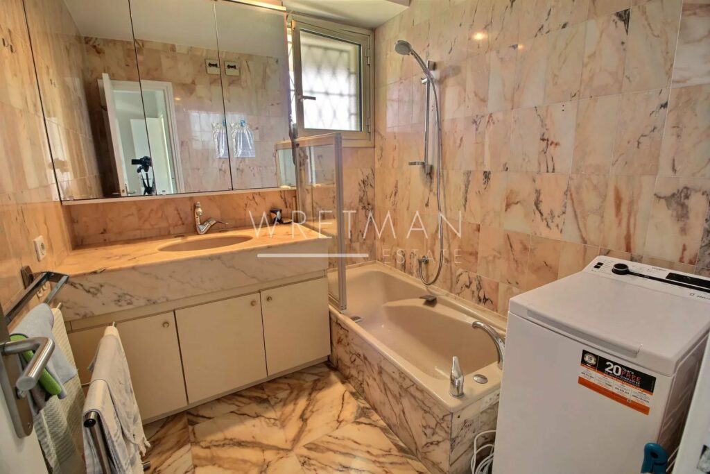bathroom with marble tiling and white bath tub