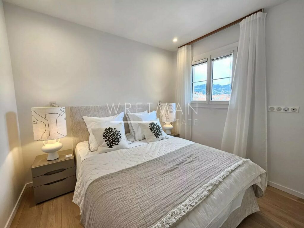 bedroom with queen size bed next to small window with city view